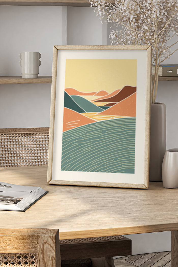 Abstract landscape poster artwork with hills and water in wooden frame on stylish desk