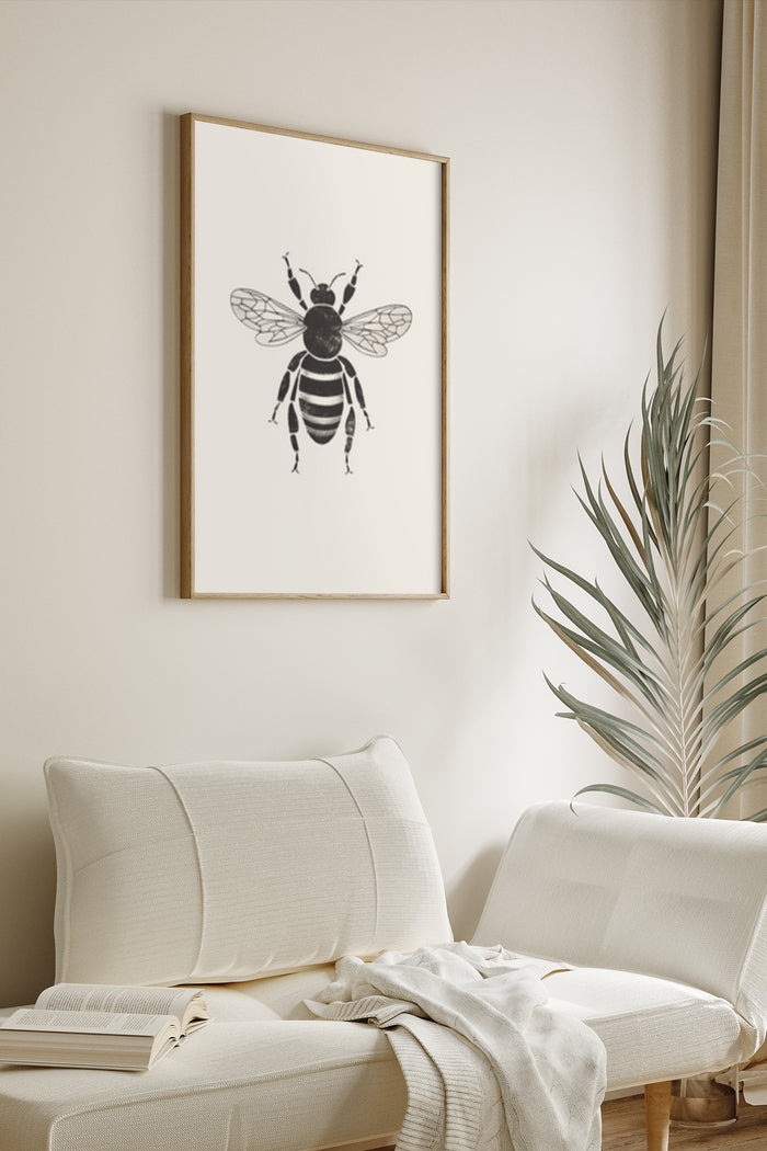 Minimalist black and white bee illustration poster framed on a wall above a modern couch with decorative plant