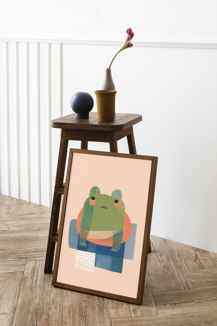 A cute cartoon frog poster in a modern interior setting, leaning against a wooden stool next to a vase and decorative items