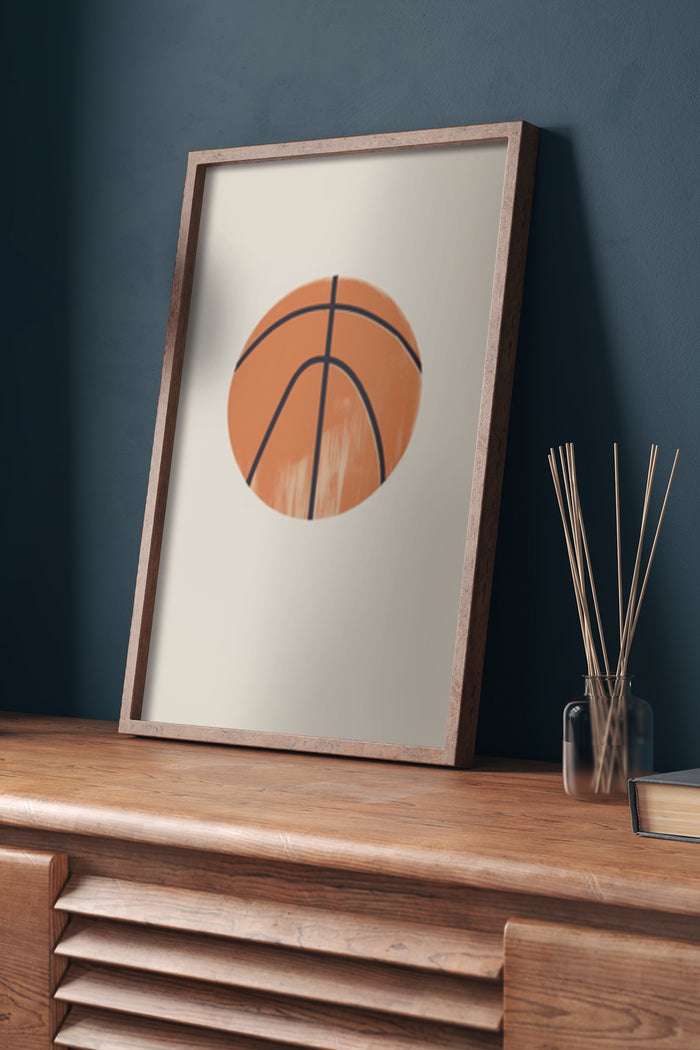 Minimalist orange basketball artwork in a framed poster on a wooden dresser with decorative items