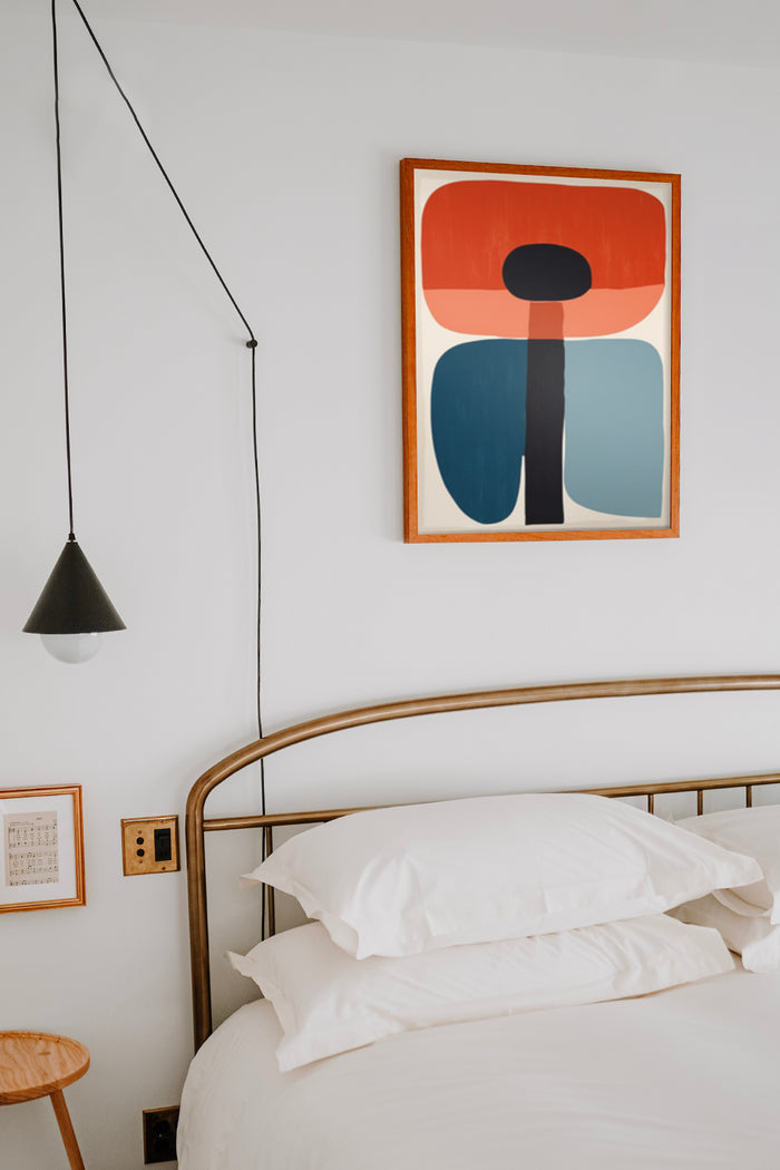 Minimalist abstract art poster with bold shapes framed on bedroom wall above a stylish metal bed frame