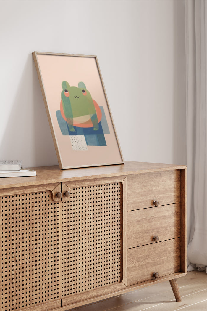 Modern cartoon frog artwork in a stylish frame placed on a wooden sideboard in a contemporary room setting