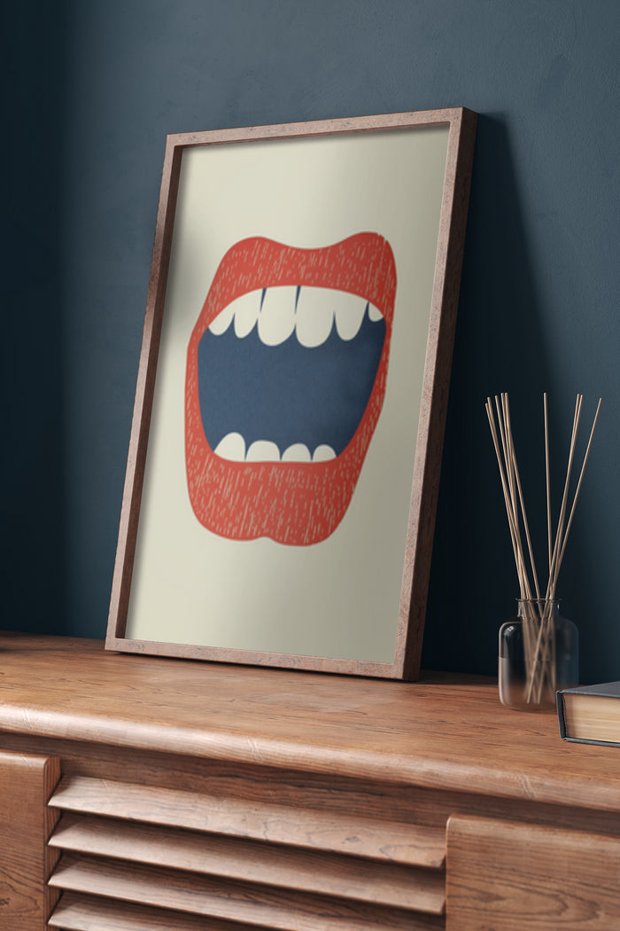 Modern abstract art poster featuring a stylized image of an open mouth with red lips and white teeth, framed and displayed on a wooden sideboard