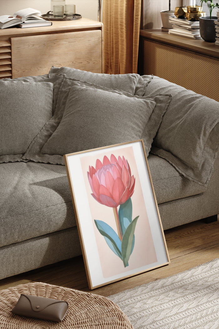 Stylish pink protea flower poster framed and leaning on cozy sofa in a modern living room setup