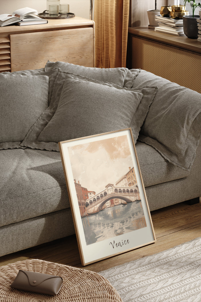 A framed Venice travel poster depicting the Rialto Bridge, placed against a couch in a cozy living room setting