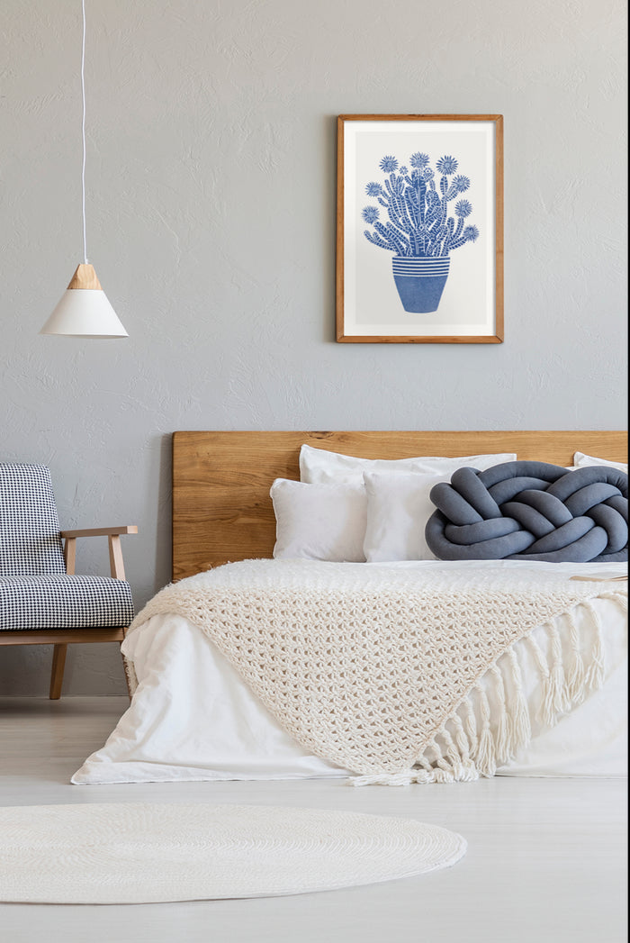 Blue cactus print in a minimalist style framed on a bedroom wall with cozy and modern interior design