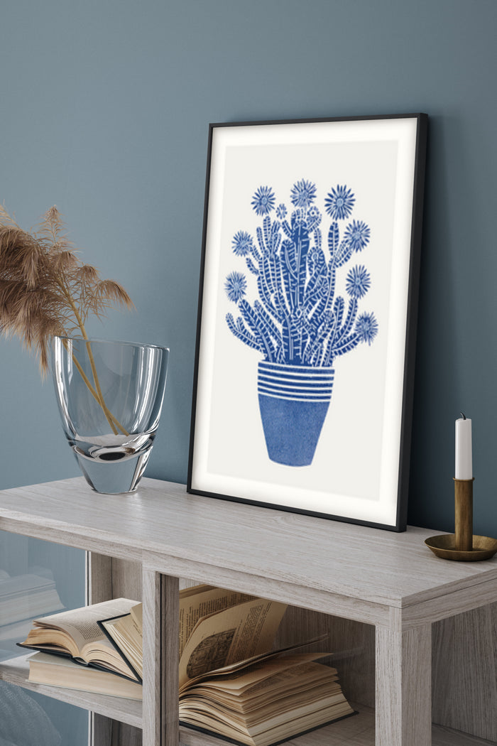 Blue and white cactus artwork poster in a modern frame on a wooden sideboard