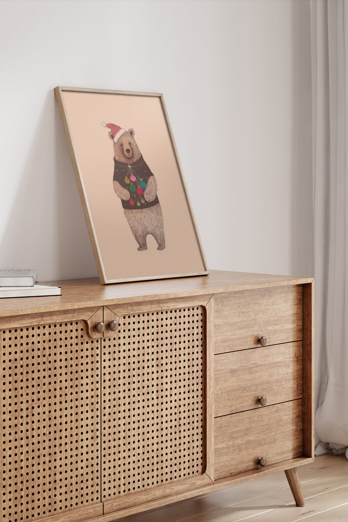 Illustration of a bear wearing a Santa hat and a sweater with ornaments displayed in a frame on a wooden cabinet in a contemporary room setting