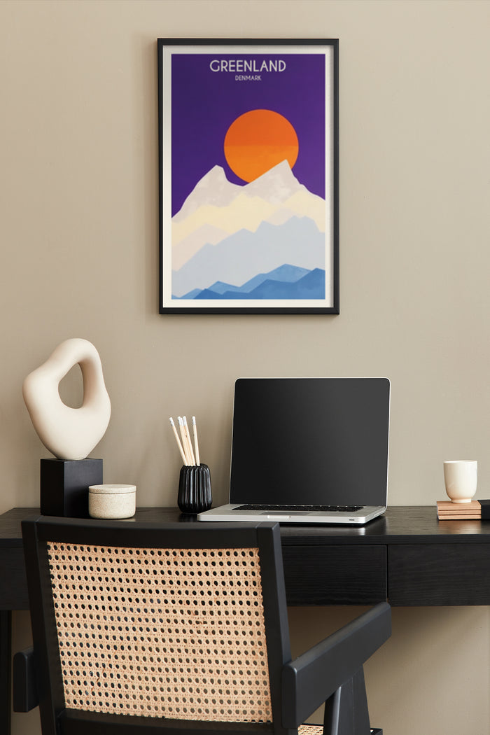Minimalist Greenland travel poster with orange sun over snowy mountains in a stylish home office setup