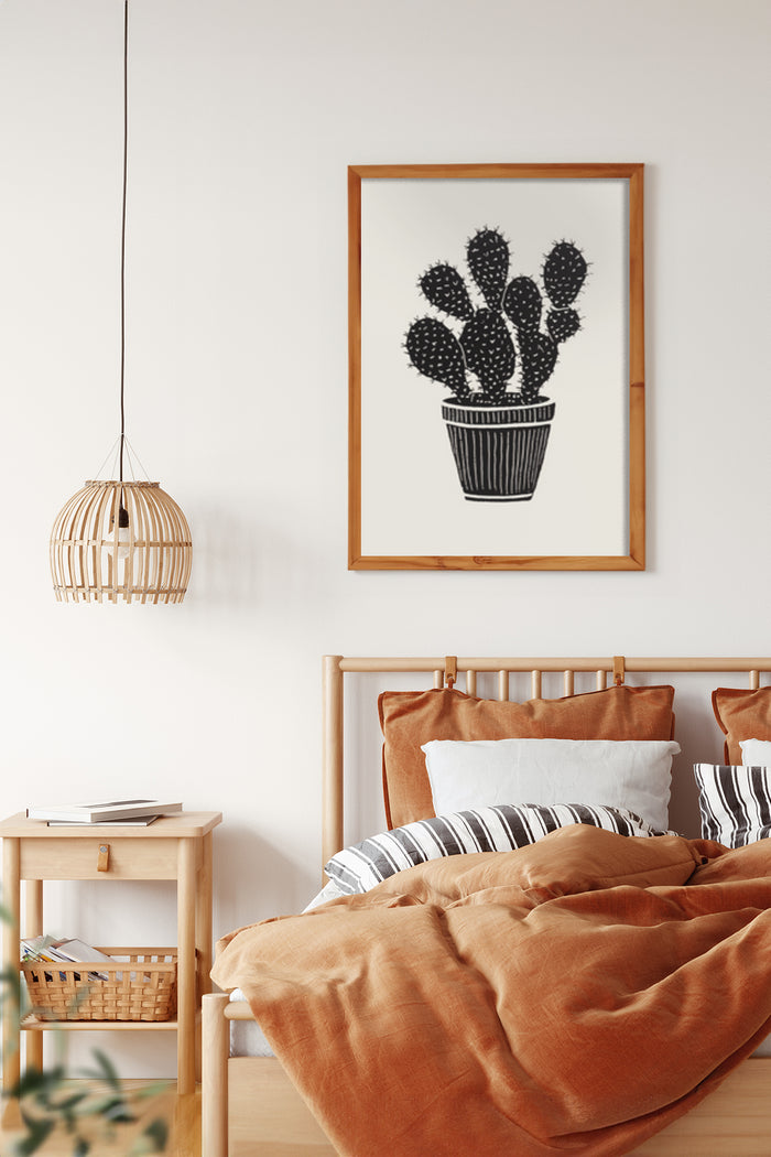 Minimalist black and white cactus illustration in wooden frame above bed with terracotta bedding in contemporary bedroom