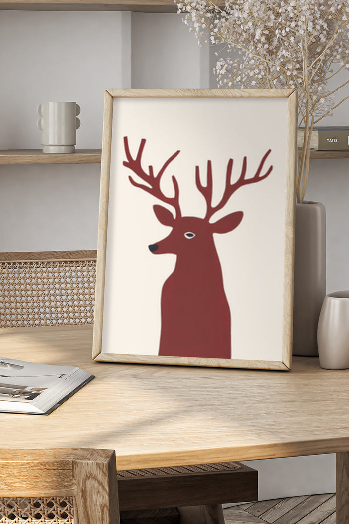 Minimalist red deer graphic art poster in a wooden frame on a modern tabletop