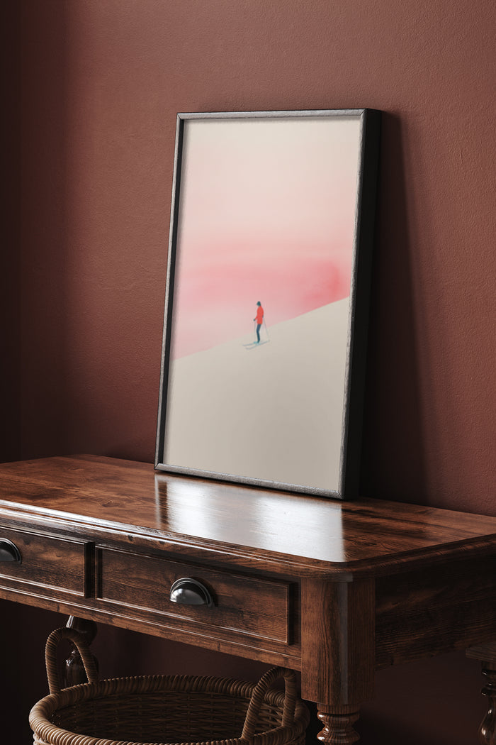Minimalist poster artwork of a lone figure walking in a desert at sunset displayed on a wooden console table against a terracotta wall