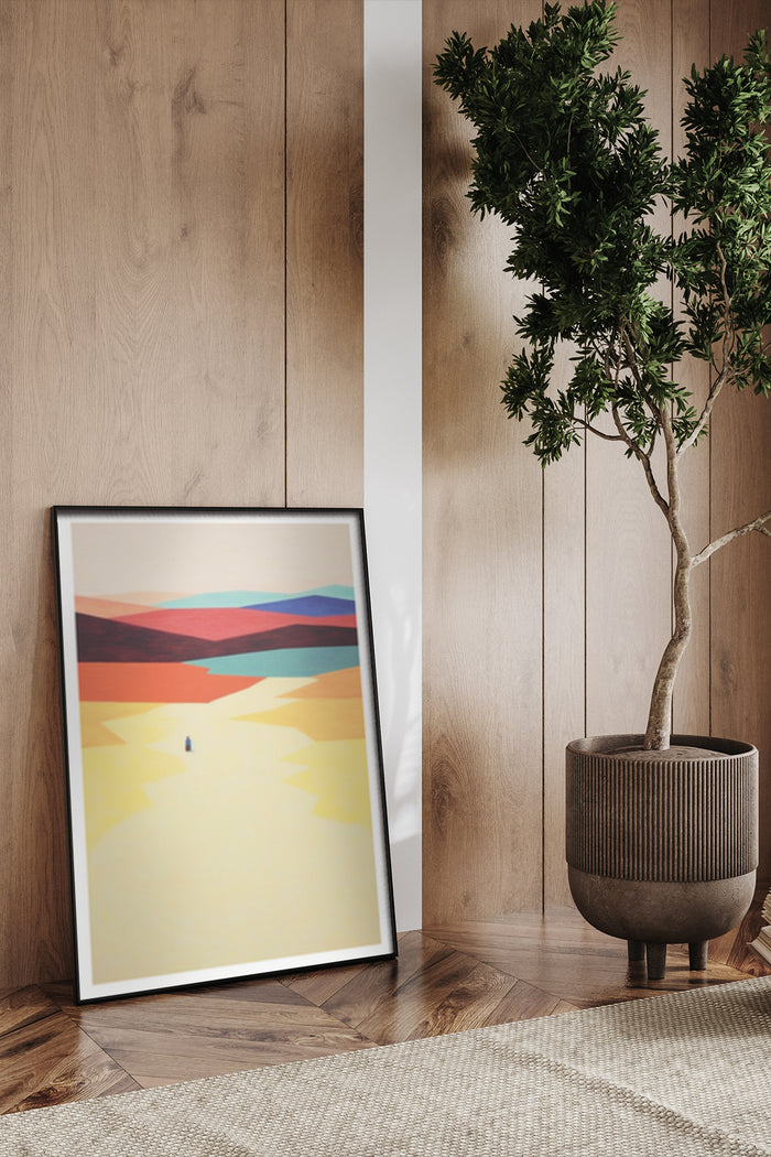 Stylized abstract desert sunset framed poster leaning against wooden wall beside potted green tree