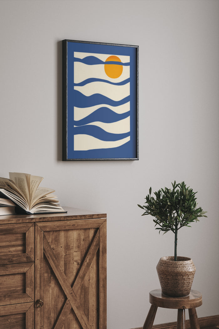 Modern abstract poster featuring stylized sun above blue waves in a dark frame on a home wall
