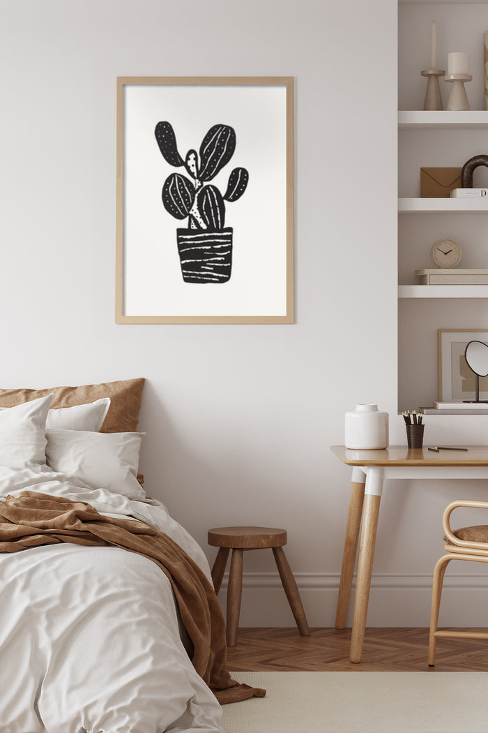 Modern black and white cactus art print in frame on bedroom wall