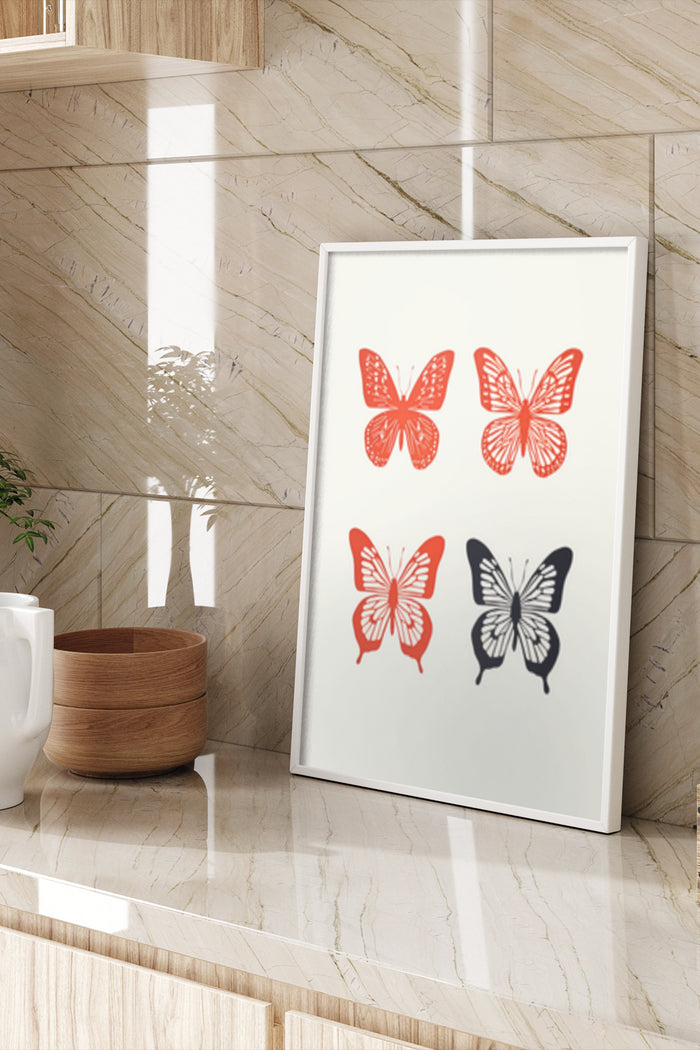 Contemporary red and black butterfly illustrations on a white poster hung on a marble wall beside a wooden bowl and ceramic mug