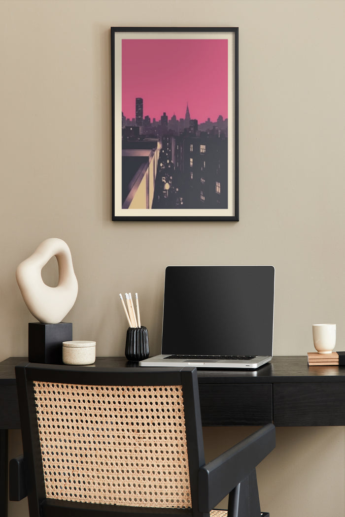 Stylish modern artwork of a cityscape with pink sky framed and hanging above a home office desk with decorative items