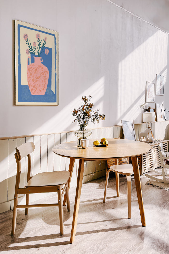 Bright modern dining room with abstract poster art on wall, round wooden table, and Scandinavian-style chairs
