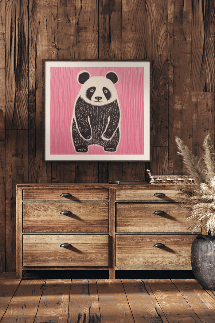 Contemporary black and white panda illustration on a pink background, framed and displayed above wooden drawers in a rustic style room