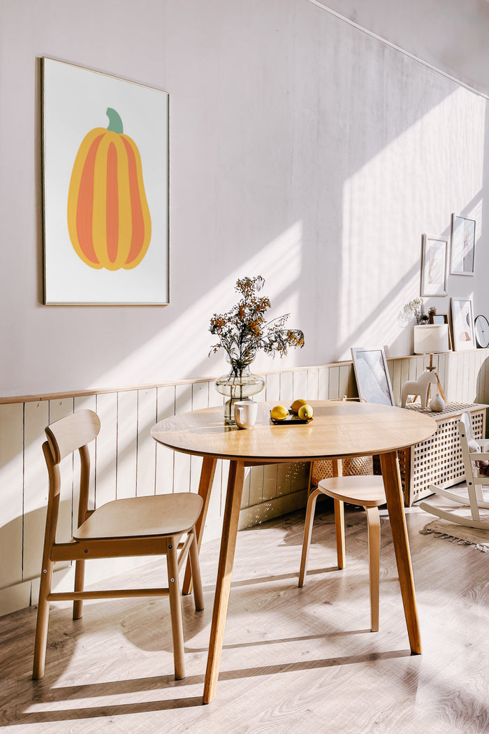 Modern pumpkin artwork poster displayed in bright dining room with wooden furniture and decorative plants