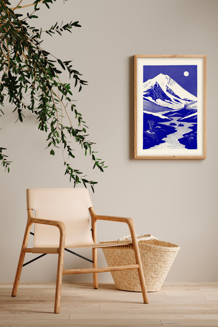 Vintage blue and white mountain landscape poster framed in a modern interior setting with a stylish chair and wicker basket